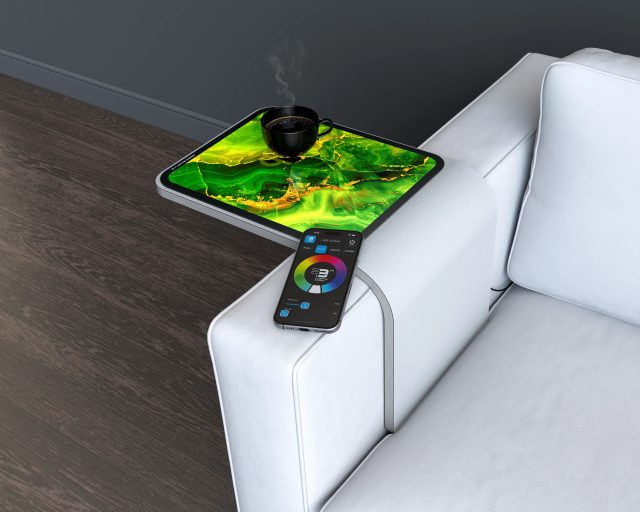 Close-up of a green decorative glass sofa-arm table holding a cup beside a color controller.